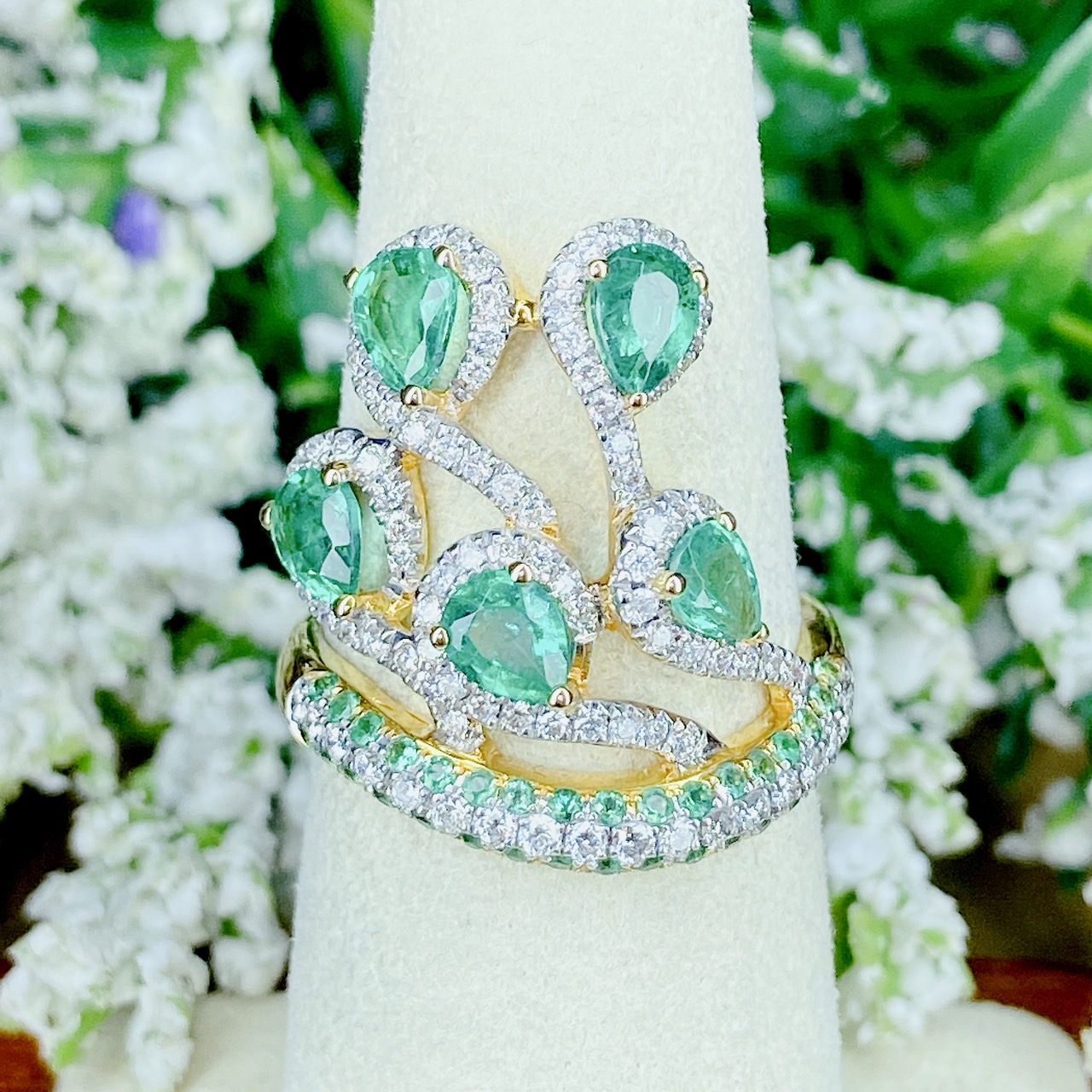 แหวนเพชรไขว้ล้อมมรกต The ring rotates upward. โดยฝังเพชรแถวสลับมรกตที่ตัวเรือนด้านล่าง แล้วค่อยหมุนไต่ระดับขึ้นด้านบนเป็นเหมือนสวนดอกไม้ Floral motif