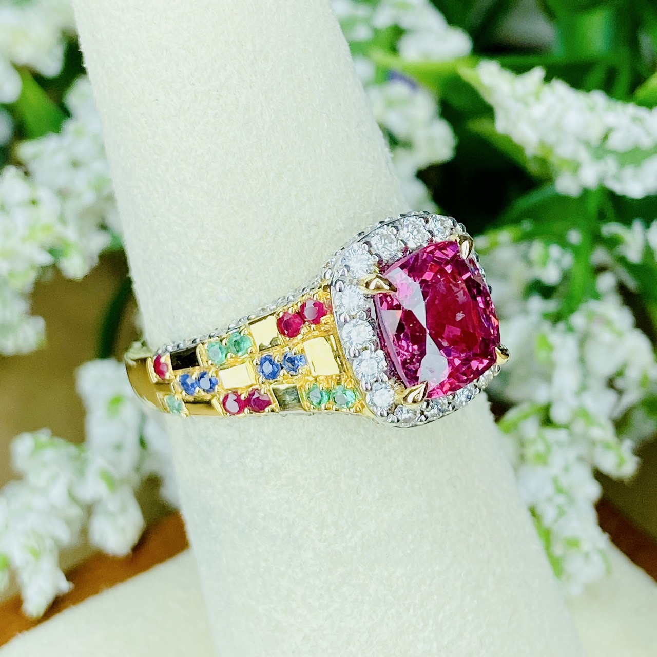 Pink Spinel (สปิเนลสูงศักดิ์) รูปทรงหมอน เจียระไนแบบเหลี่ยมผสม (จะให้แสงระยิบระยับที่สวยมากๆ) ล้อมด้วยเพชรน้ำ100 ฝังตรงกะเปาะด้านข้าง บ่าฝังพลอยทับทิมพม่า/ไพลินซีลอน/มรกตแซมเบีย สลับหว่างกับตัวเรือนทอง ทรงชูไม่สูงมาก ใส่แล้วโอบรับกับนิ้ว