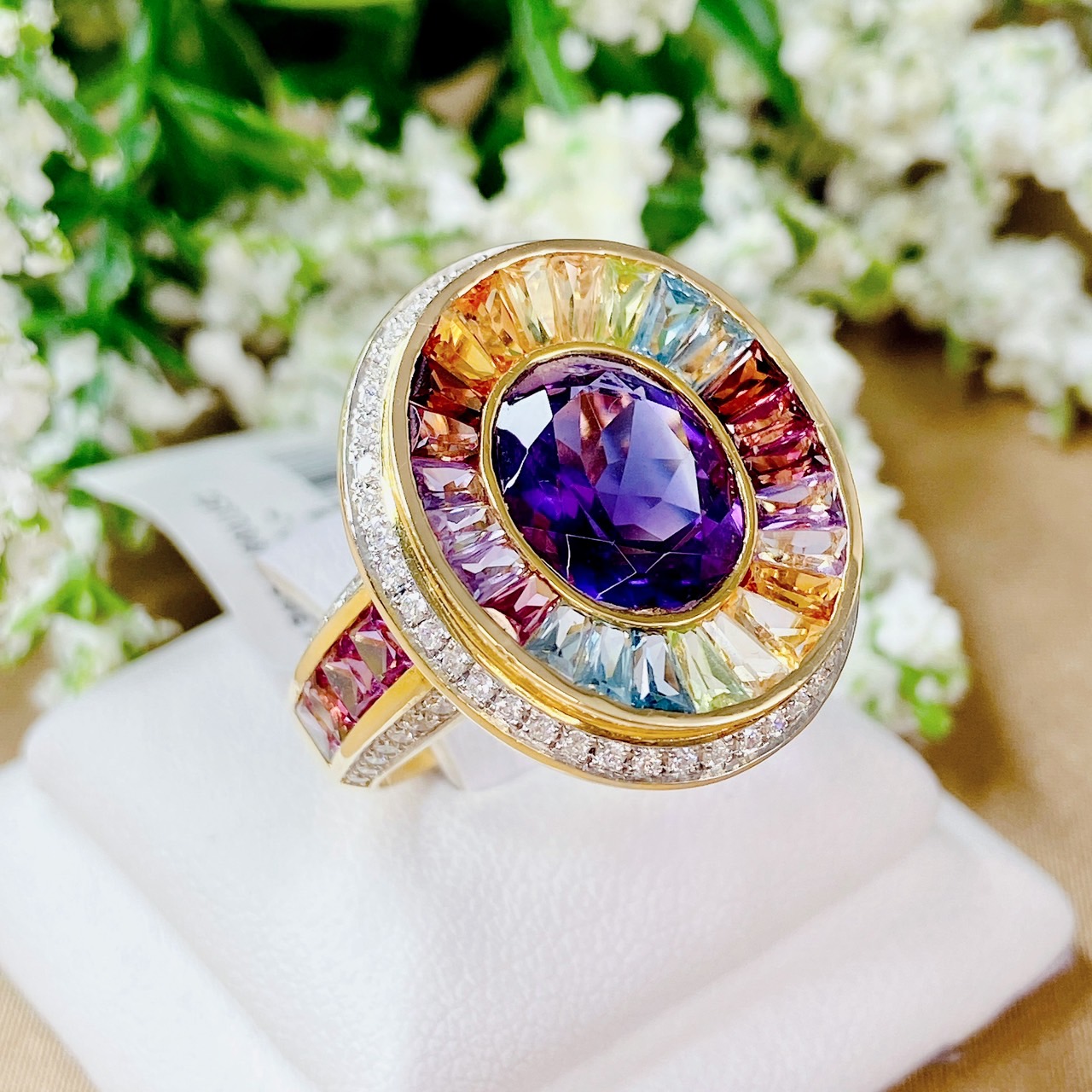 แหวนพลอยมัลติเหลี่ยมแทปเปอร์ล้อมอเมทิสต์สีม่วง ฝังเพชรล้อมเป็น Surprise Diamond ประดับบ่าด้านข้างด้วยอเมทิสต์เหลี่ยมปริ้นเซส ตัดขอบด้วยเพชรน้ำ100