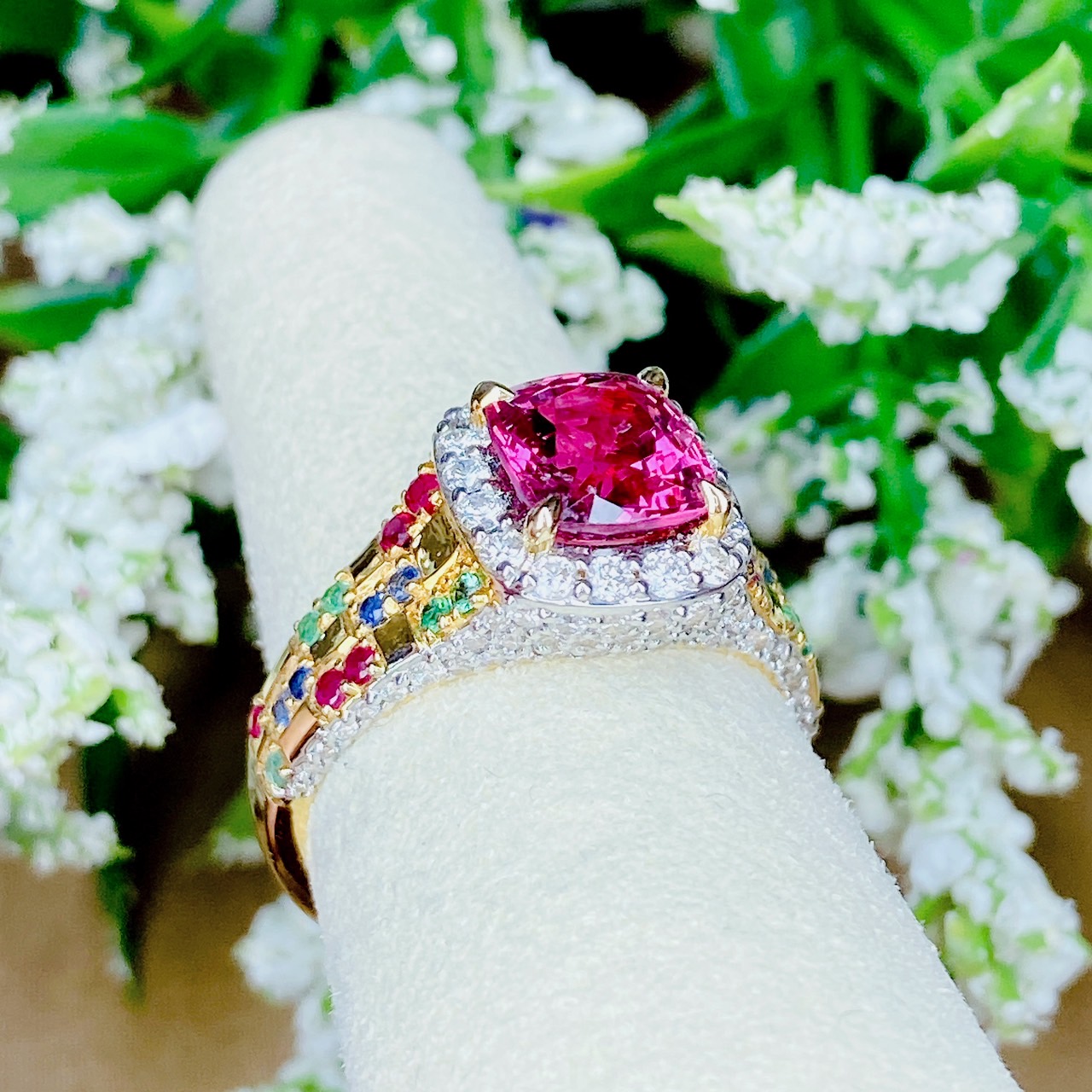 Pink Spinel (สปิเนลสูงศักดิ์) รูปทรงหมอน เจียระไนแบบเหลี่ยมผสม (จะให้แสงระยิบระยับที่สวยมากๆ) ล้อมด้วยเพชรน้ำ100 ฝังตรงกะเปาะด้านข้าง บ่าฝังพลอยทับทิมพม่า/ไพลินซีลอน/มรกตแซมเบีย สลับหว่างกับตัวเรือนทอง ทรงชูไม่สูงมาก ใส่แล้วโอบรับกับนิ้ว