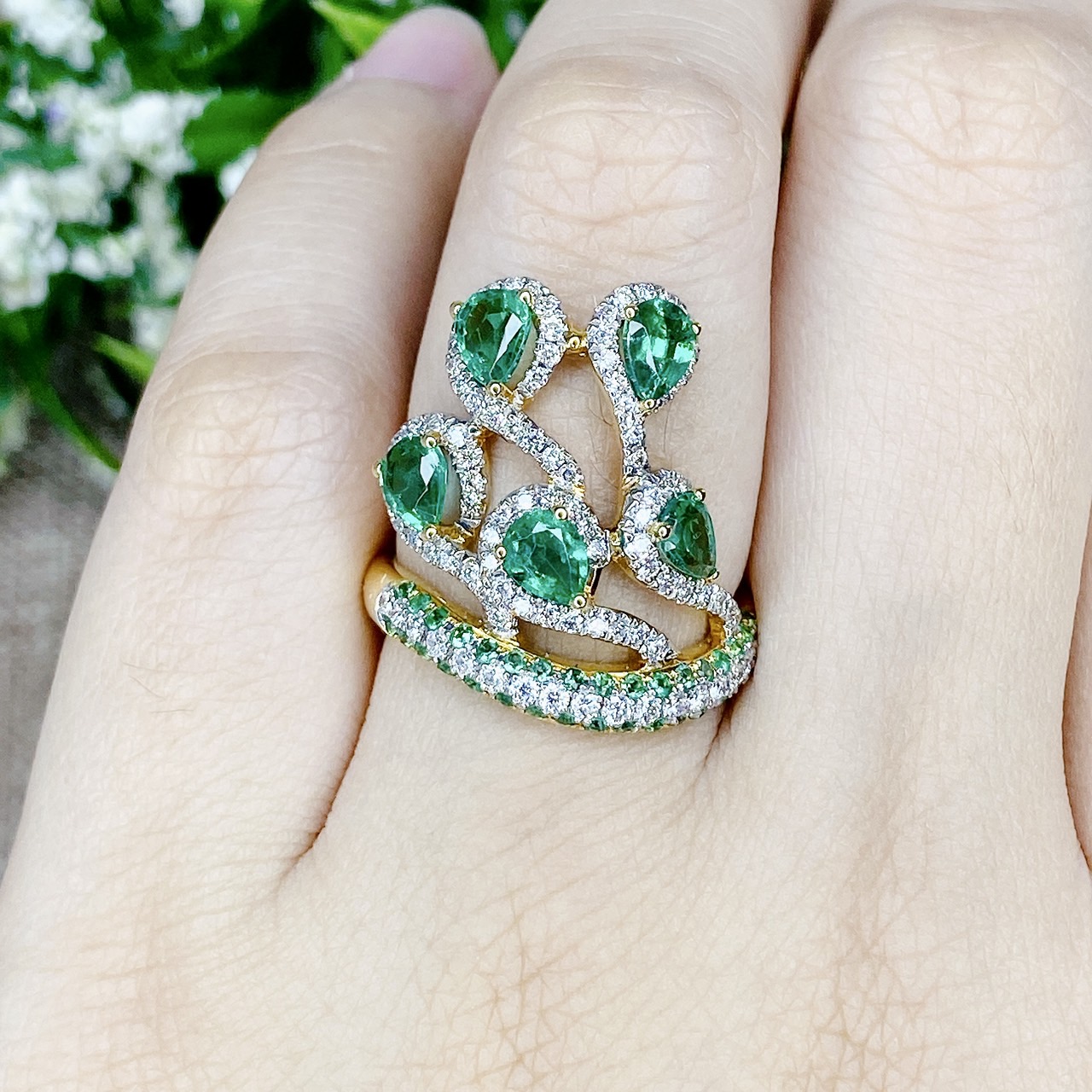 แหวนเพชรไขว้ล้อมมรกต The ring rotates upward. โดยฝังเพชรแถวสลับมรกตที่ตัวเรือนด้านล่าง แล้วค่อยหมุนไต่ระดับขึ้นด้านบนเป็นเหมือนสวนดอกไม้ Floral motif