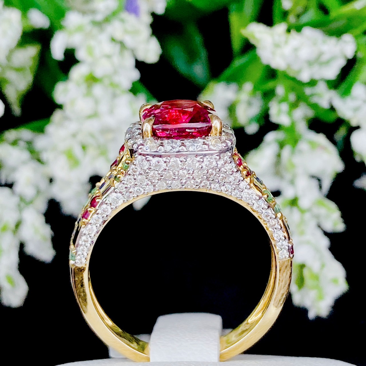 Pink Spinel (สปิเนลสูงศักดิ์) รูปทรงหมอน เจียระไนแบบเหลี่ยมผสม (จะให้แสงระยิบระยับที่สวยมากๆ) ล้อมด้วยเพชรน้ำ100 ฝังตรงกะเปาะด้านข้าง บ่าฝังพลอยทับทิมพม่า/ไพลินซีลอน/มรกตแซมเบีย สลับหว่างกับตัวเรือนทอง ทรงชูไม่สูงมาก ใส่แล้วโอบรับกับนิ้ว