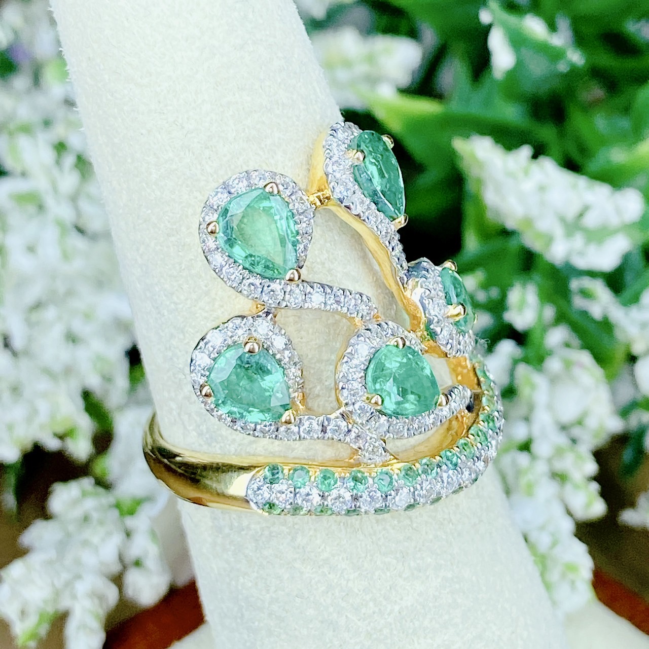 แหวนเพชรไขว้ล้อมมรกต The ring rotates upward. โดยฝังเพชรแถวสลับมรกตที่ตัวเรือนด้านล่าง แล้วค่อยหมุนไต่ระดับขึ้นด้านบนเป็นเหมือนสวนดอกไม้ Floral motif