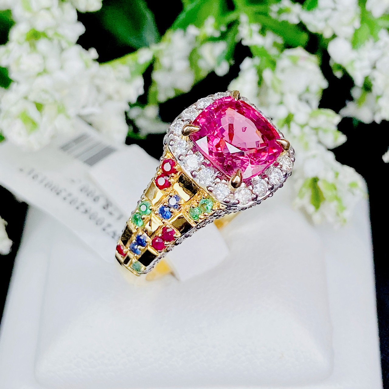 Pink Spinel (สปิเนลสูงศักดิ์) รูปทรงหมอน เจียระไนแบบเหลี่ยมผสม (จะให้แสงระยิบระยับที่สวยมากๆ) ล้อมด้วยเพชรน้ำ100 ฝังตรงกะเปาะด้านข้าง บ่าฝังพลอยทับทิมพม่า/ไพลินซีลอน/มรกตแซมเบีย สลับหว่างกับตัวเรือนทอง ทรงชูไม่สูงมาก ใส่แล้วโอบรับกับนิ้ว